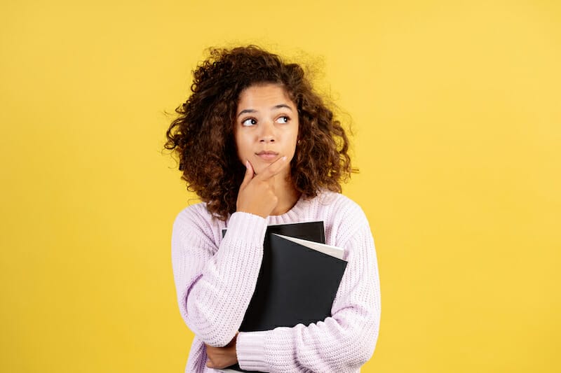 Picture of a female student looking puzzled on a yellow background 
